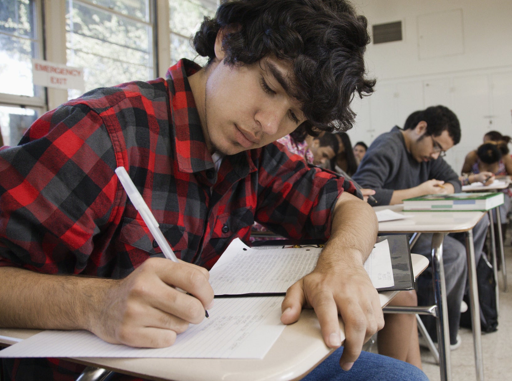 A Latinx student takes a test among other students in the classroom