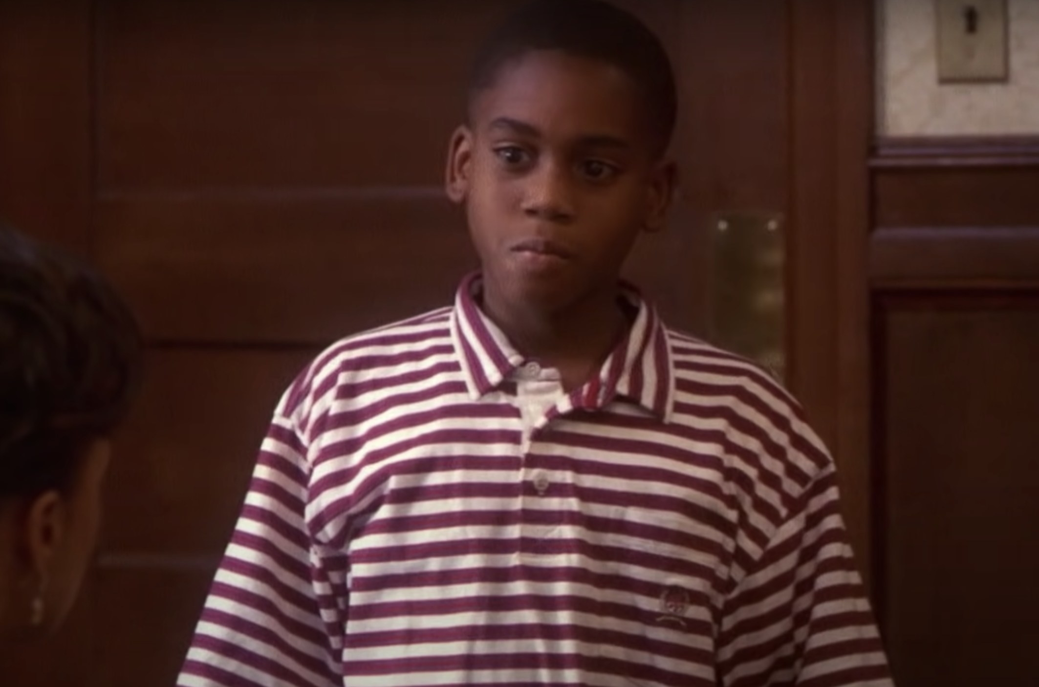 Actor Brandon Hammond is a little boy wearing a red and white striped shirt. He frowns and looks very upset.