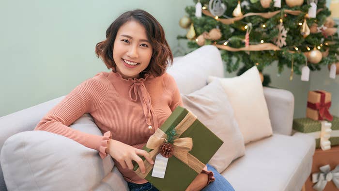 A person smiling and holding a gift.