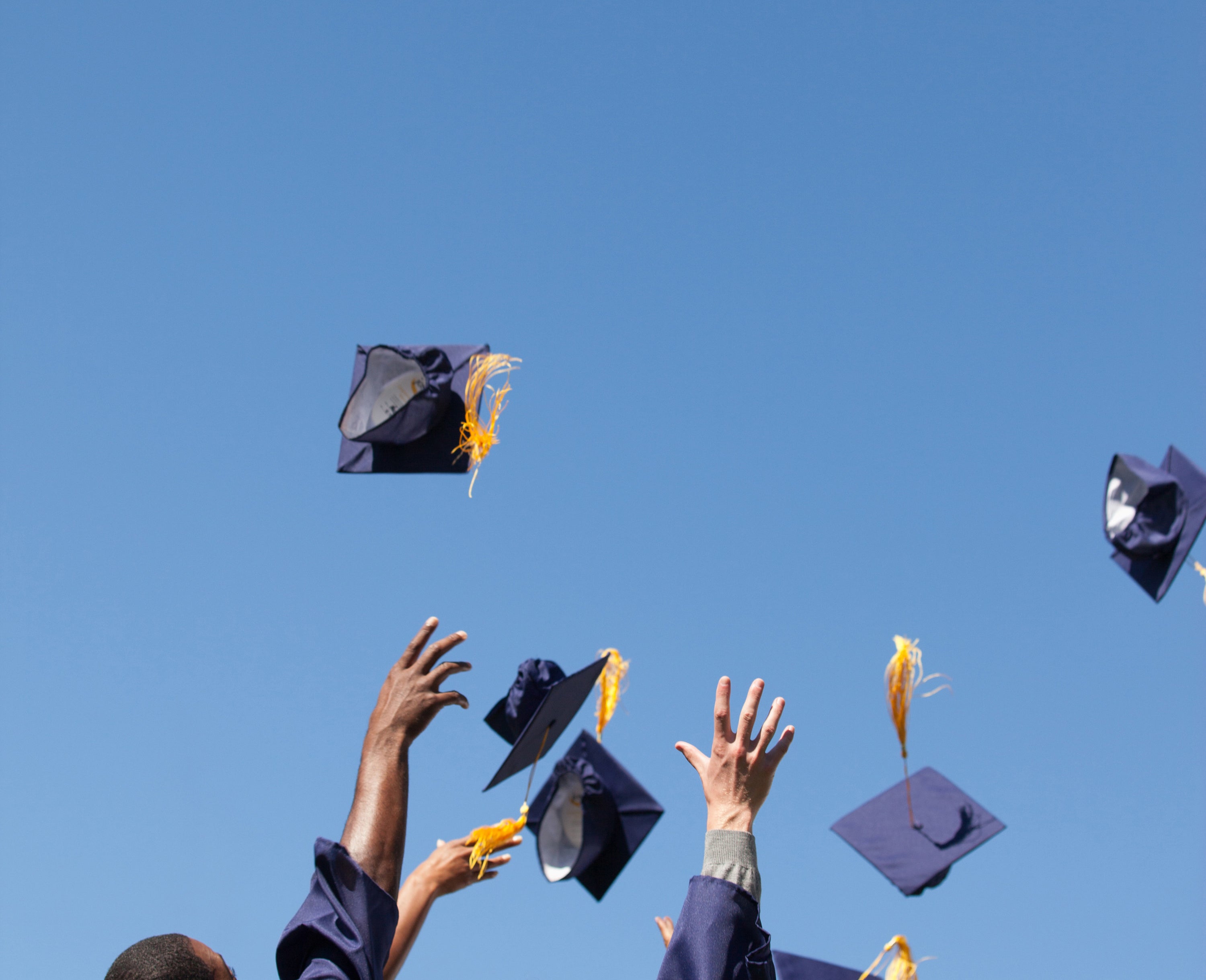 graduating high school students throwing their caps in the air