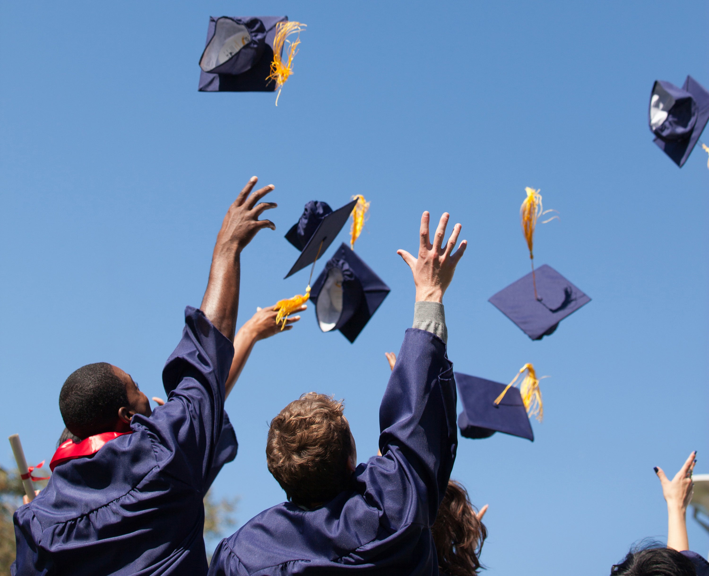 graduating high school students throwing their caps in the air