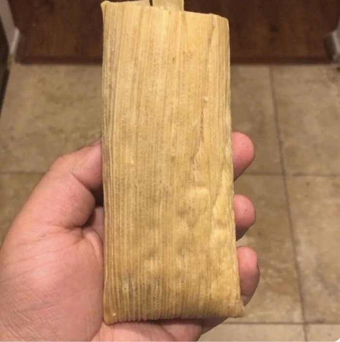 Me holding a tamal in its husk