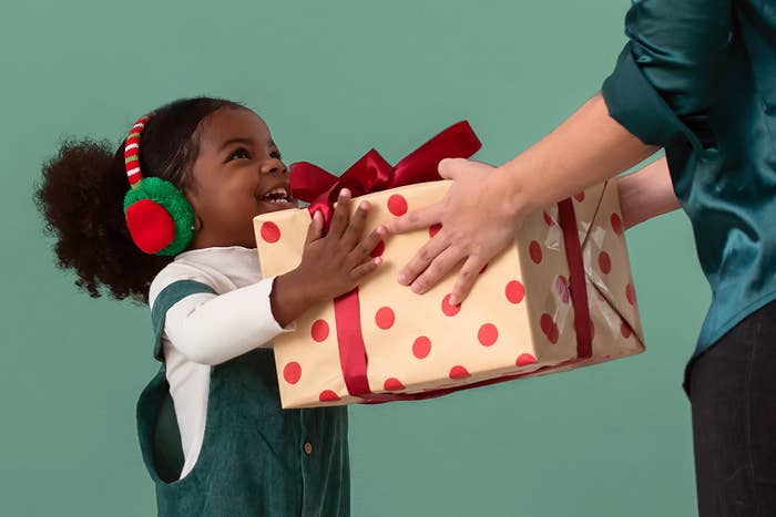 A smiling child being given a present.