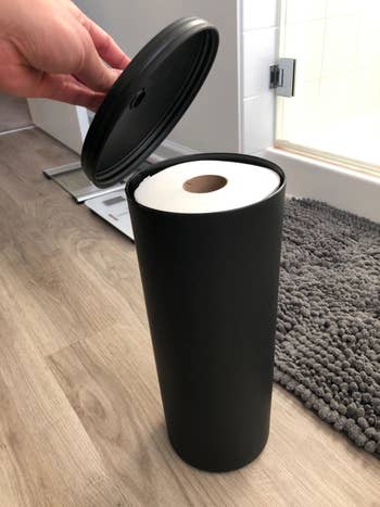Reviewer shows the canister without its lid, revealing the toilet paper that is stored inside