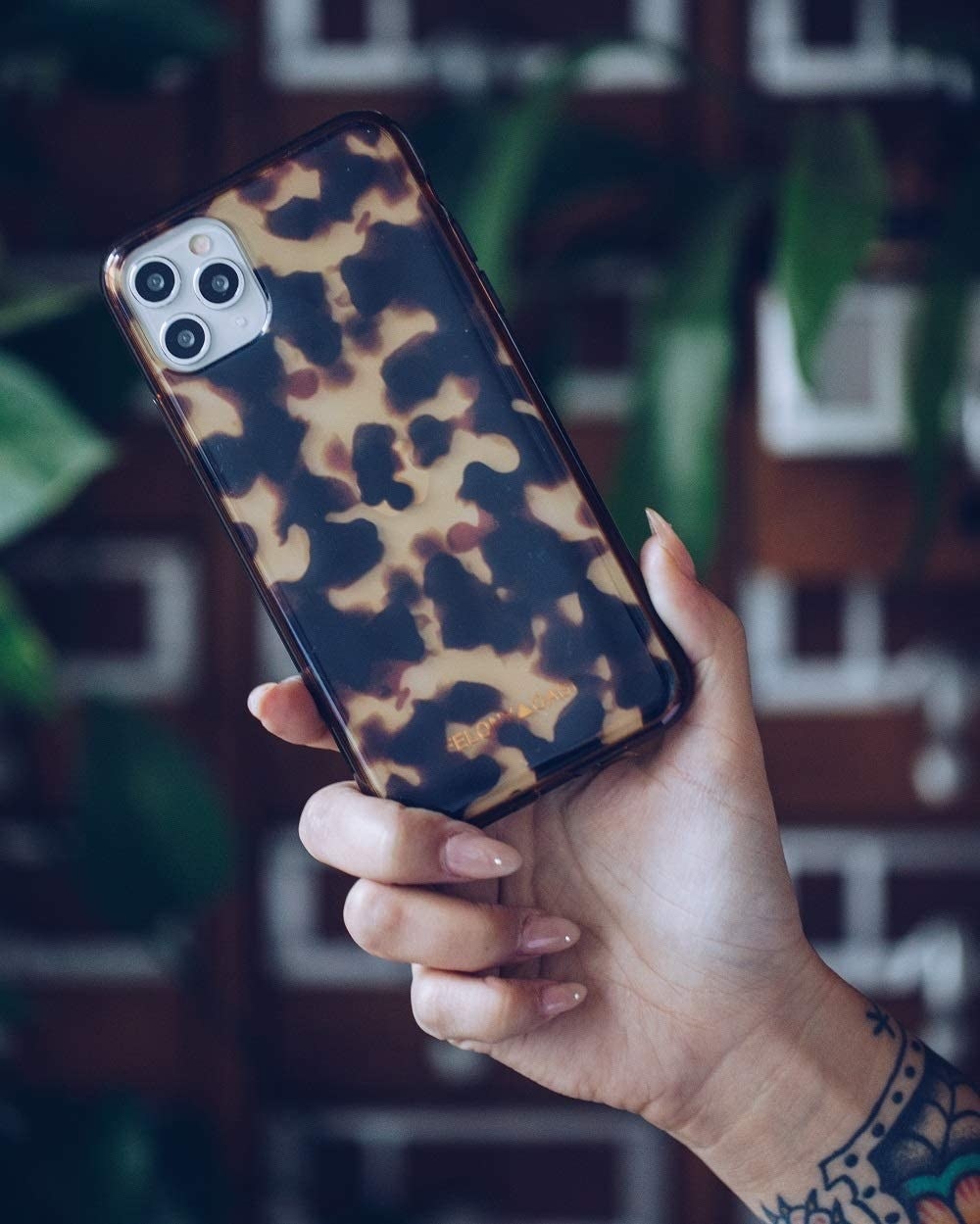 a person holding up the tortoiseshell phone case