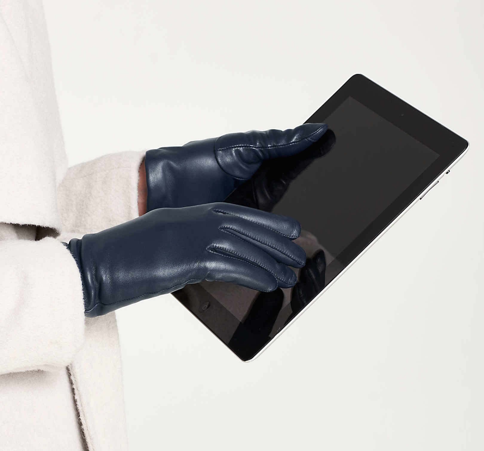 a model wearing the navy leather gloves while holding an iPad.