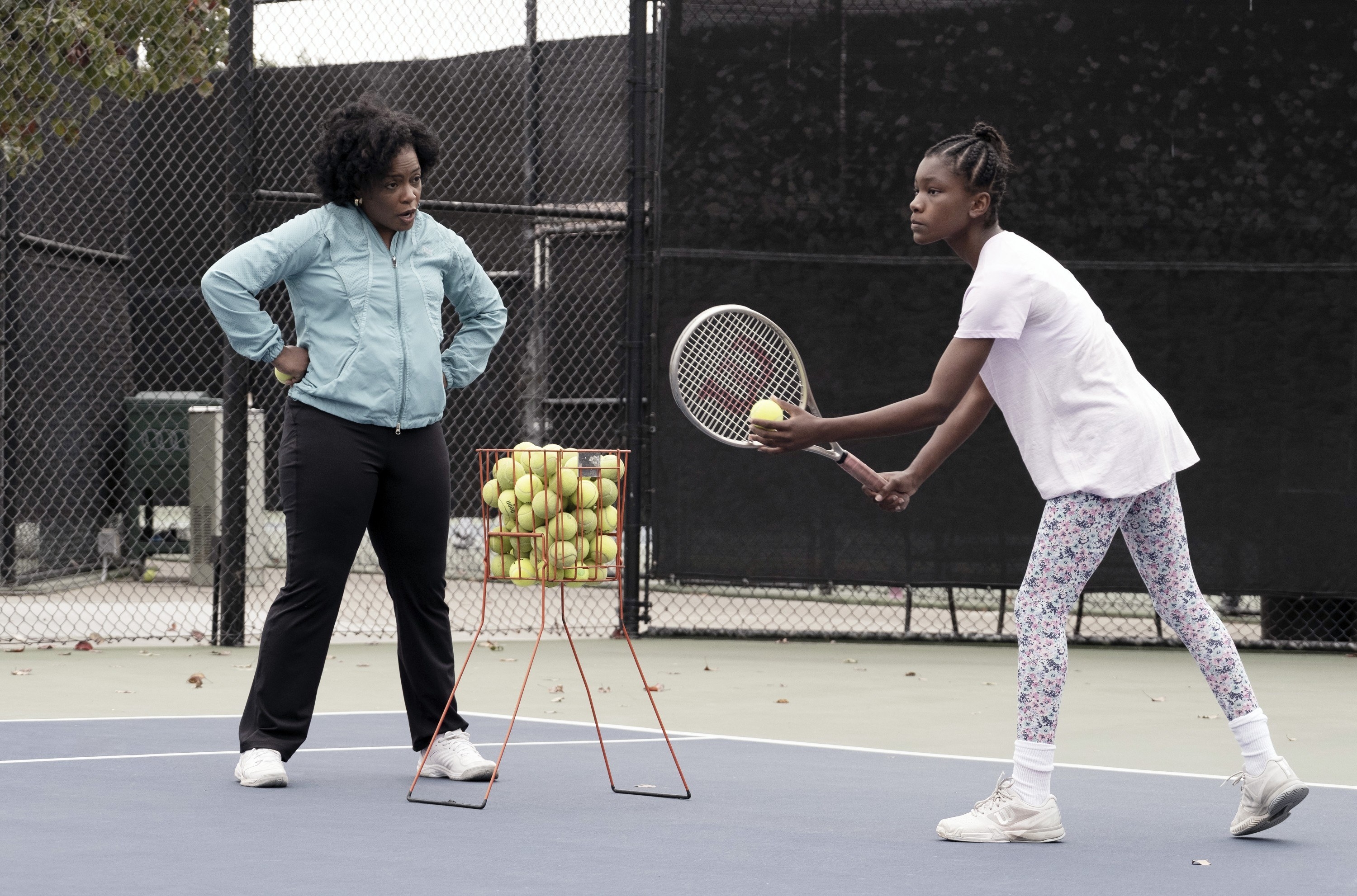 Aunjanue Ellis as Oracene &quot;Brandy&quot; Williams and Demi Singleton as Serena Williams about to serve a tennis ball