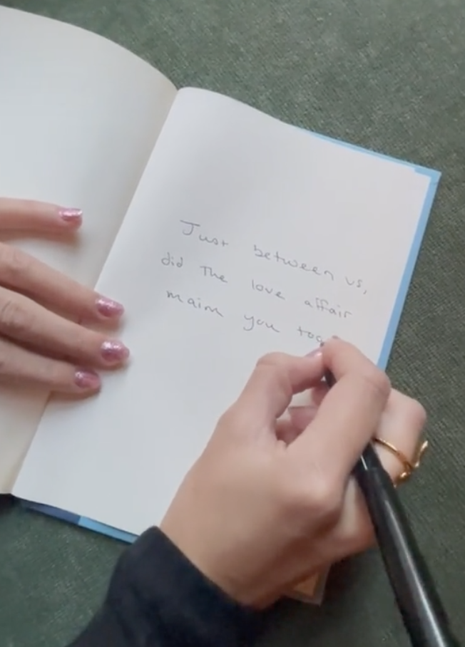 Hand writing &quot;Just between us, did the love affair maim you too?&quot; in a notebook