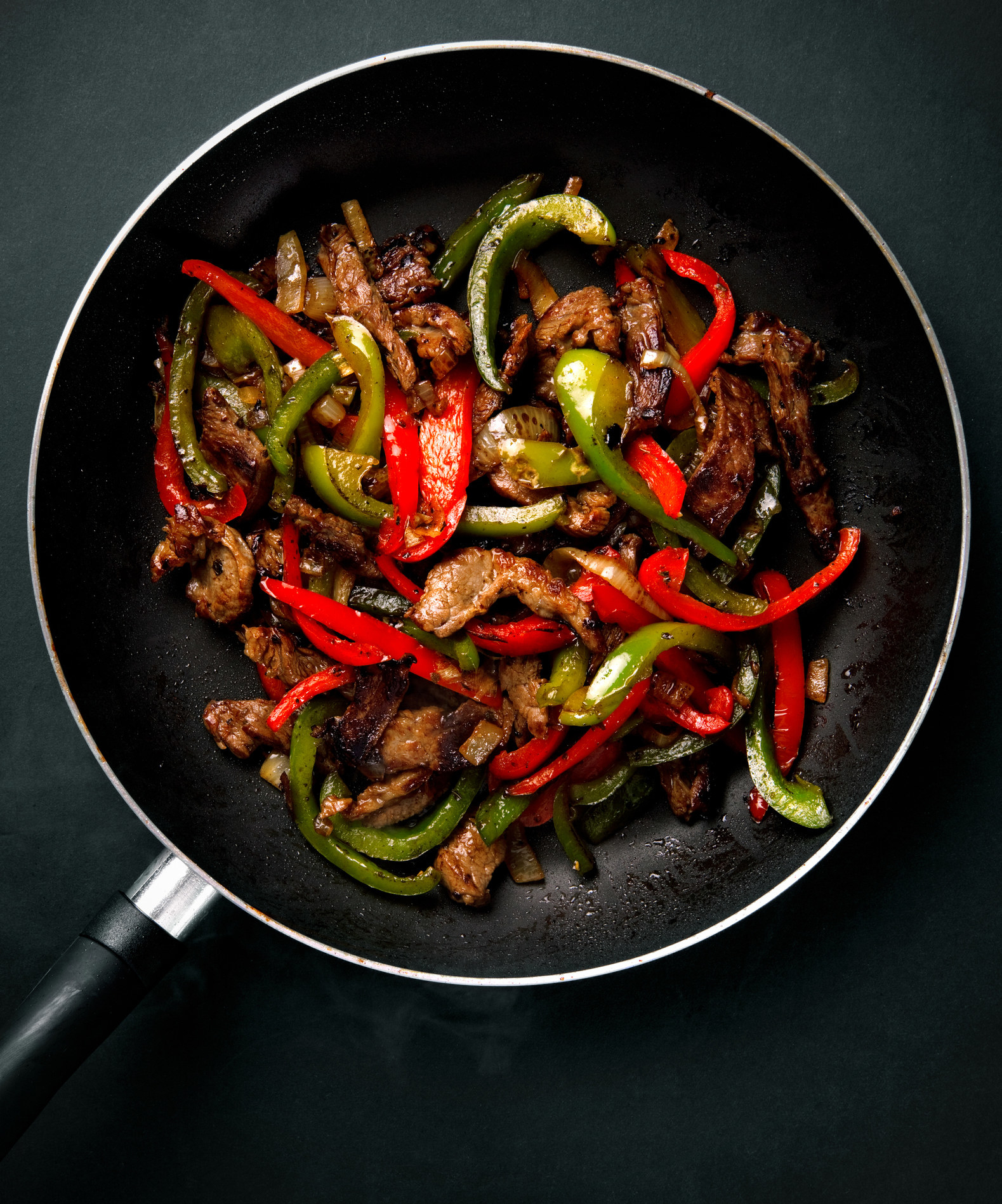 Steak and peppers in a skillet.
