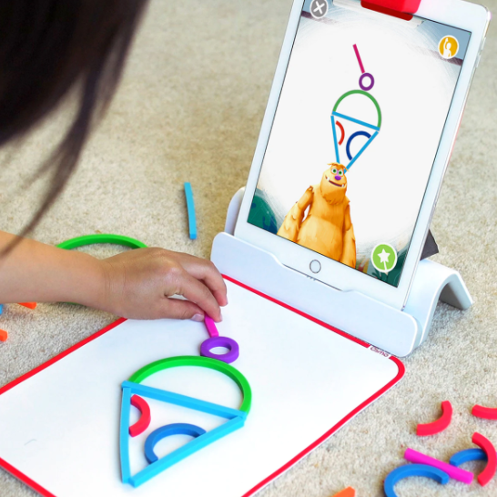 Young girl building ice cream cone shape while playing with Osmo&#x27;s Little Genius Starter Kit