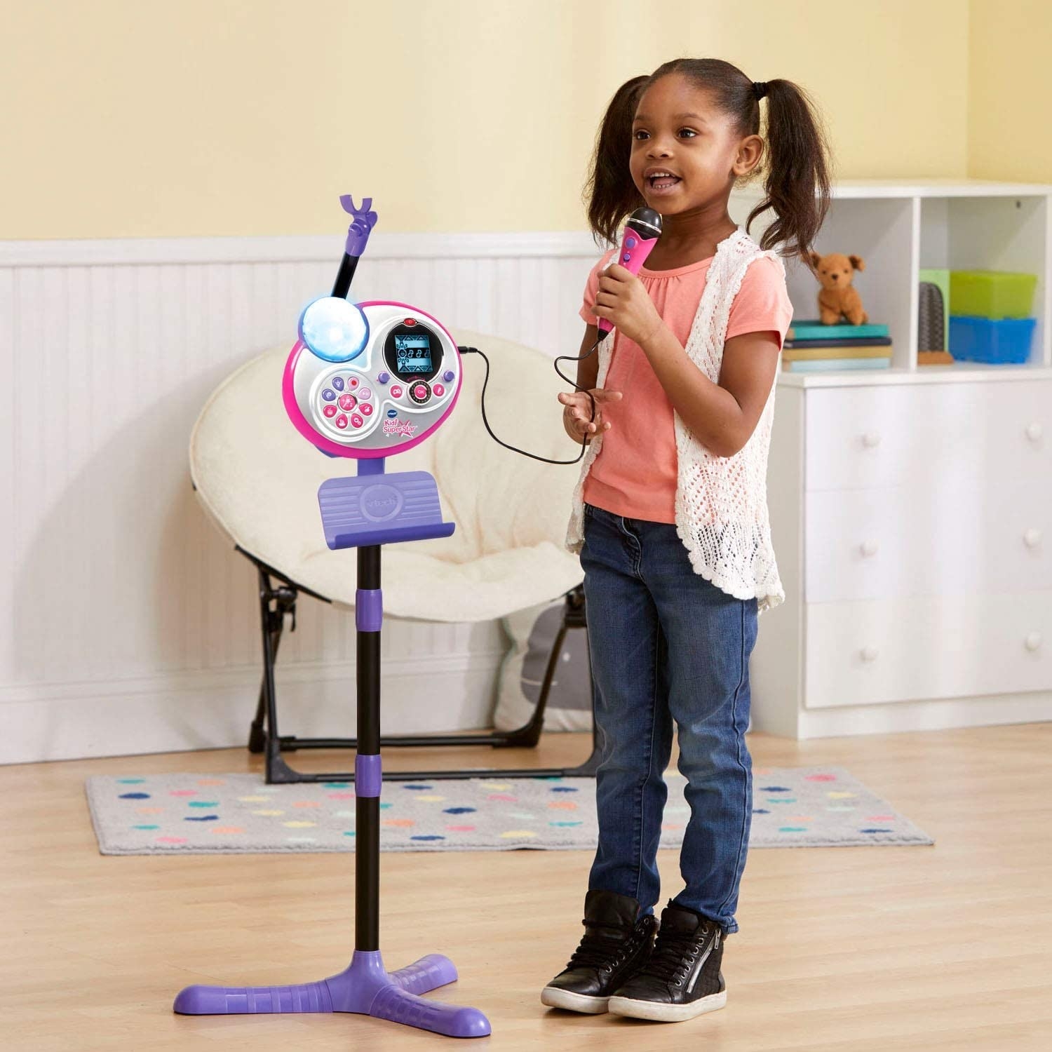 A young girl sings into a handheld microphone and karaoke set