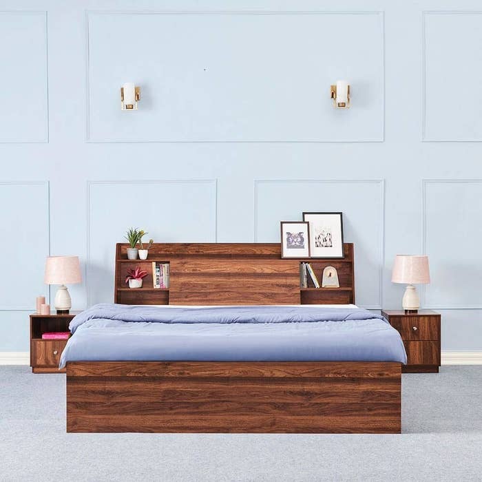 A bedframe with a bed on it next to side tables with lamps on them