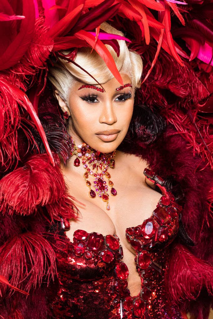 Cardi wearing a bejeweled outfit with feathers and rocking a short blonde wig