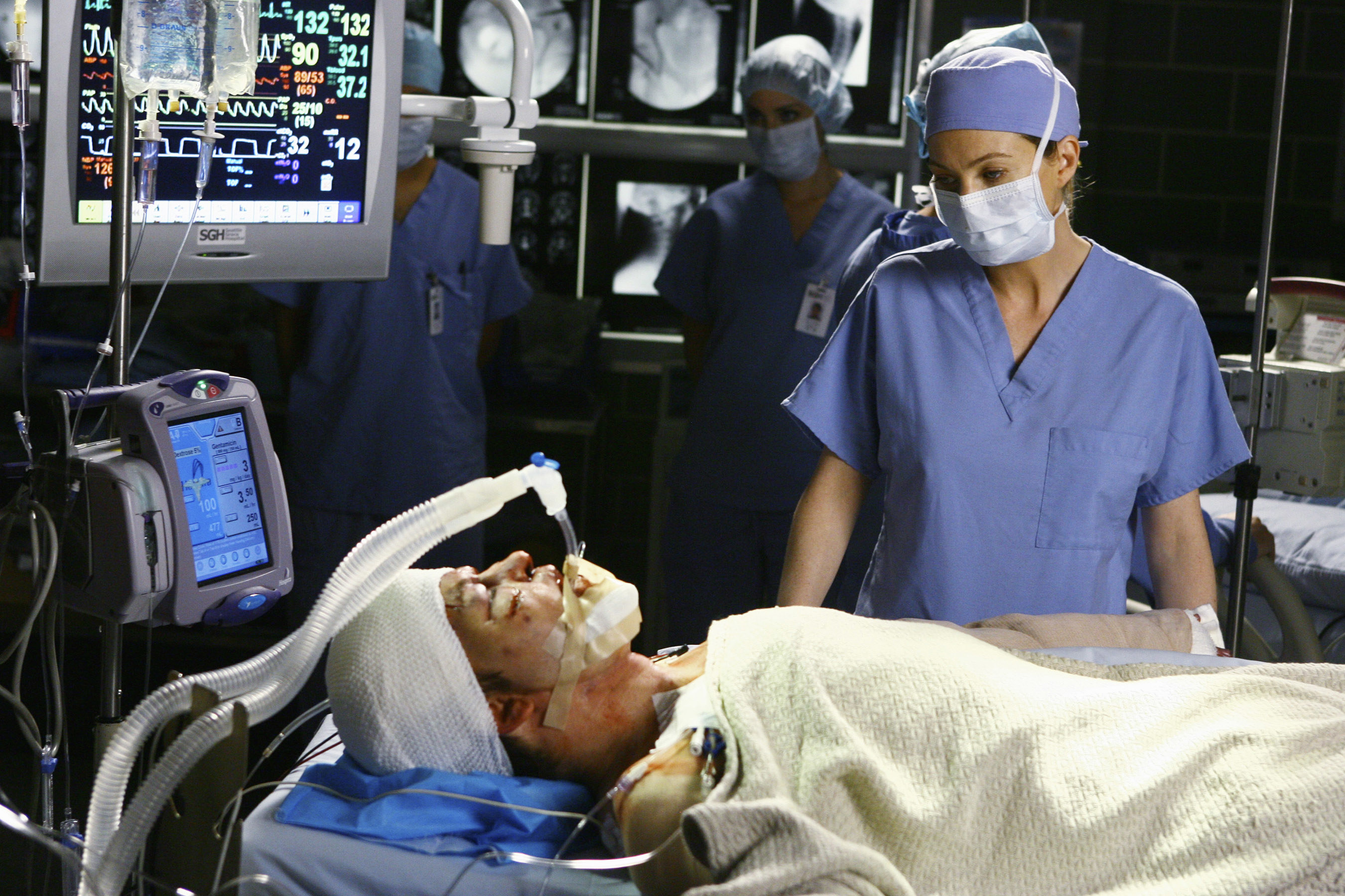 Meredith looking sadly at George lying on a bed in the OR