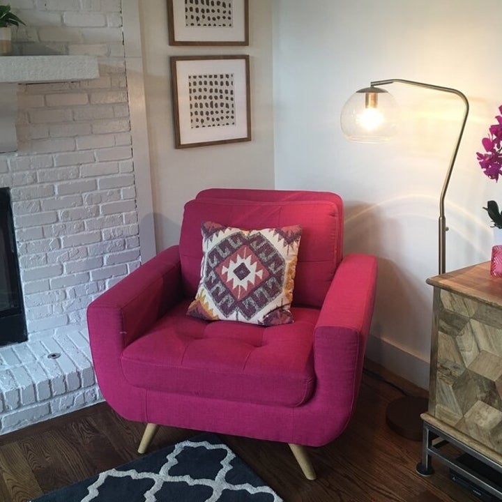 the chair in red with a patterned throw pillow on it and a standing lamp next to it