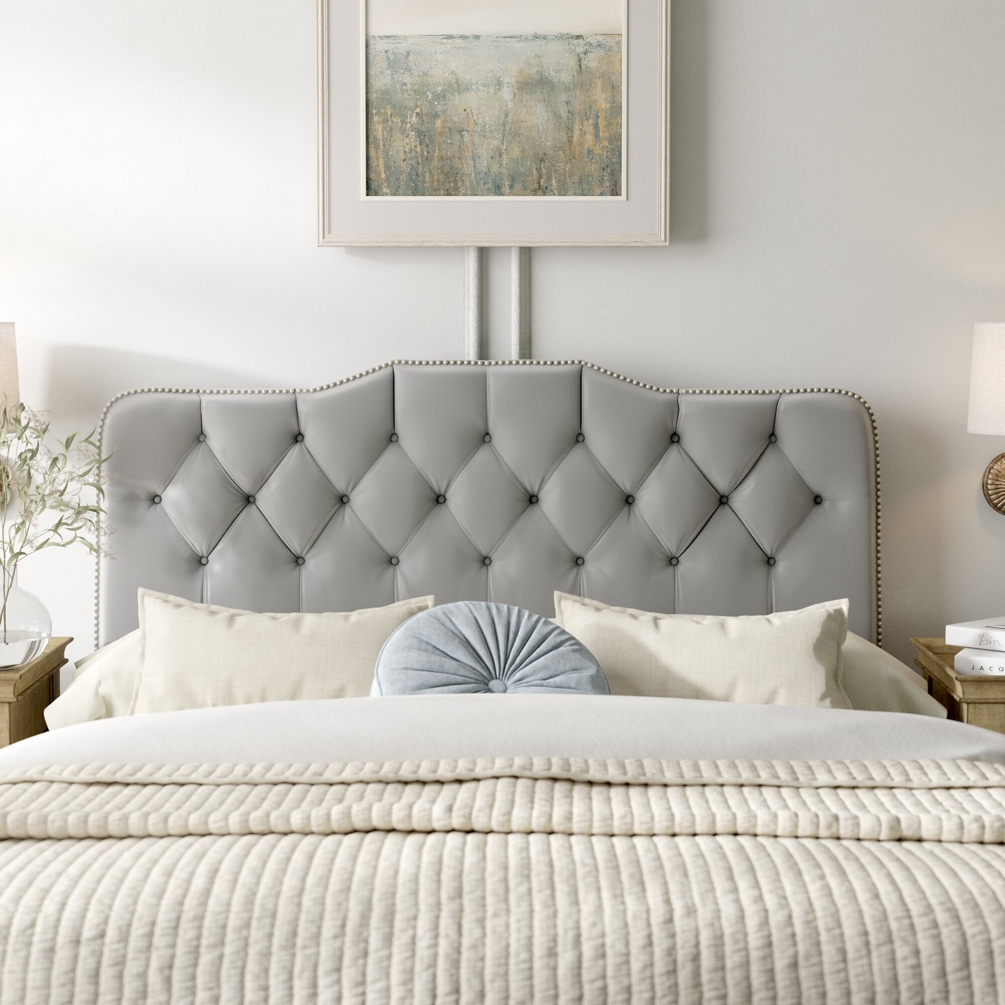 the headboard in gray with white and gray pillows on it and white bedding