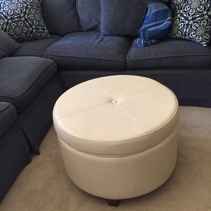 the ivory ottoman in front of a navy blue couch