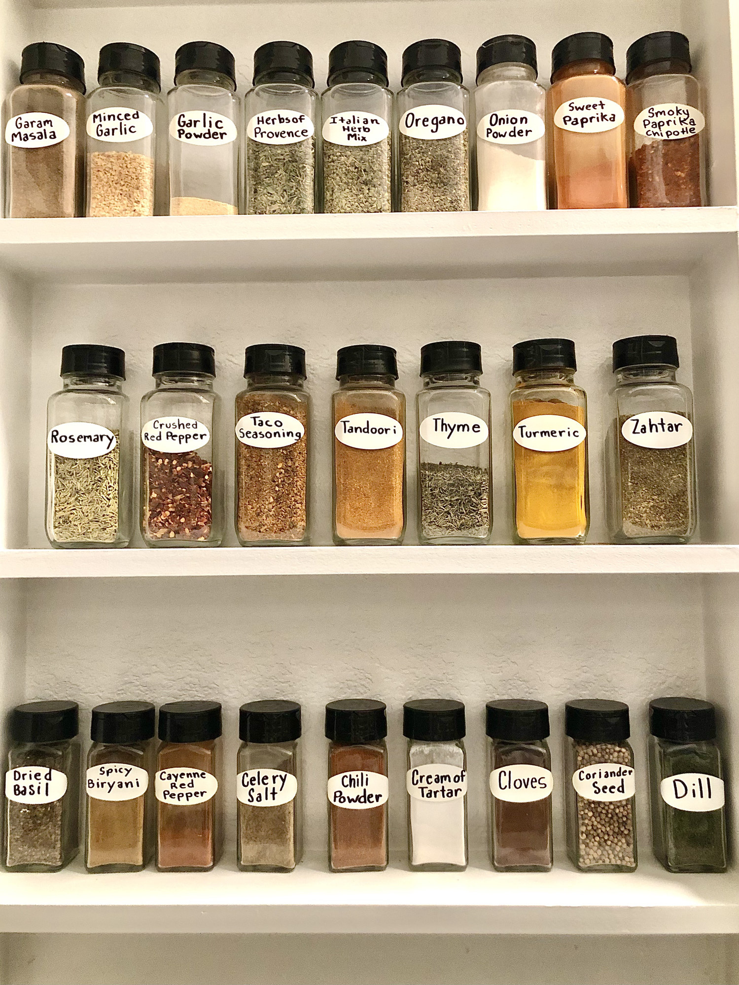 A spice cabinet with labeled spices.