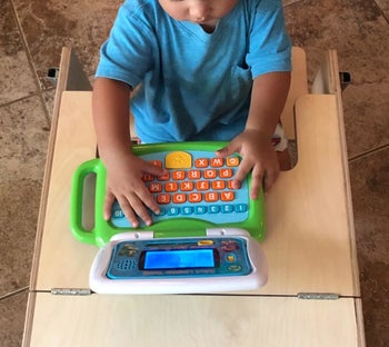 reviewer's photo of their child playing with the green laptop