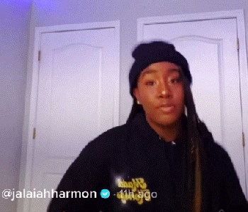 TikTok jalaiah Harmon wearing a hoodie and cap while dancing in front of a door