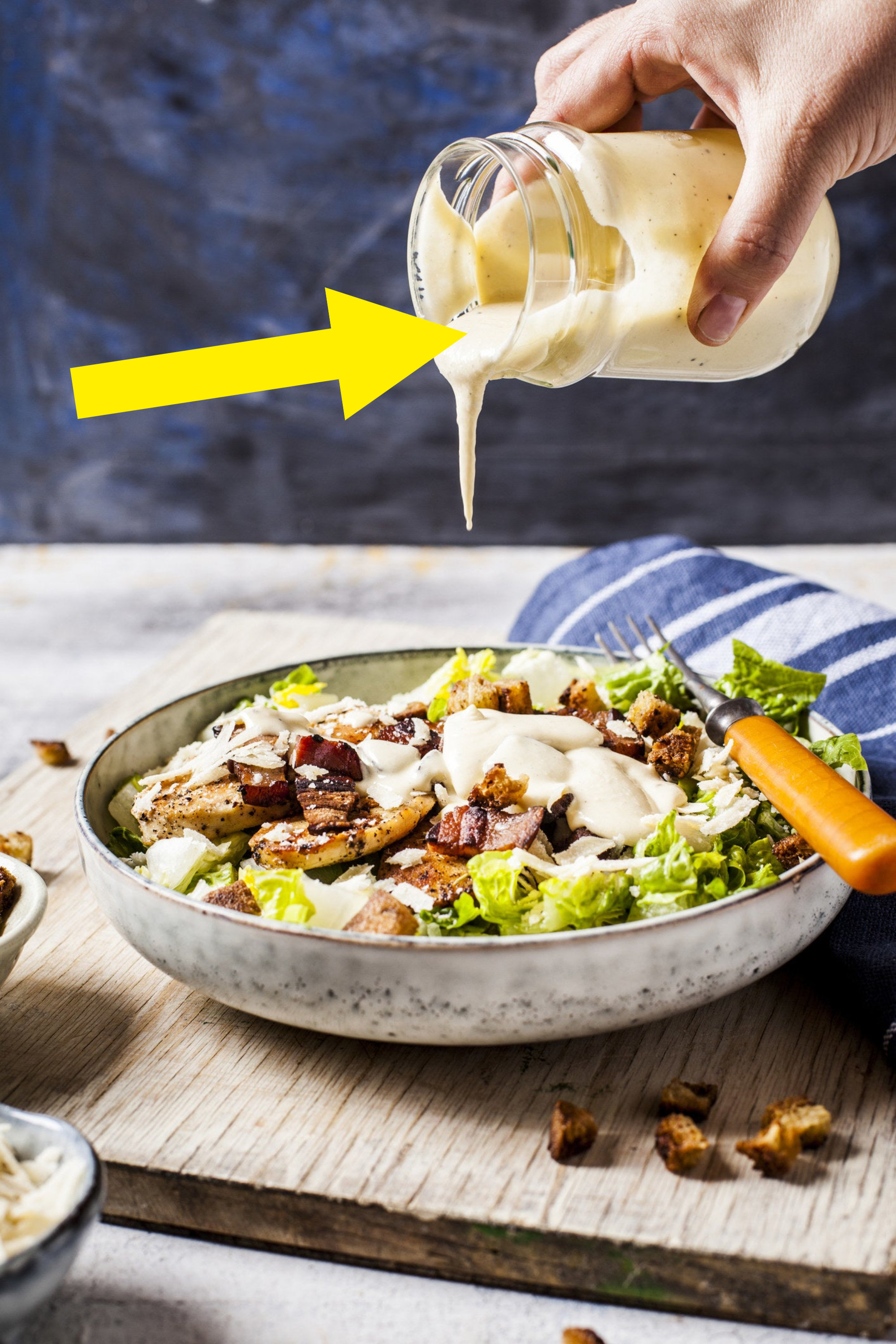 Pouring Caesar dressing onto a salad.