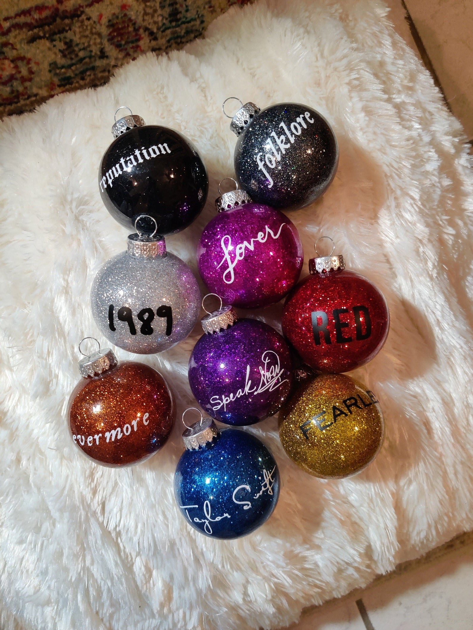 nine glittery ornaments with taylor swift album titles on each one