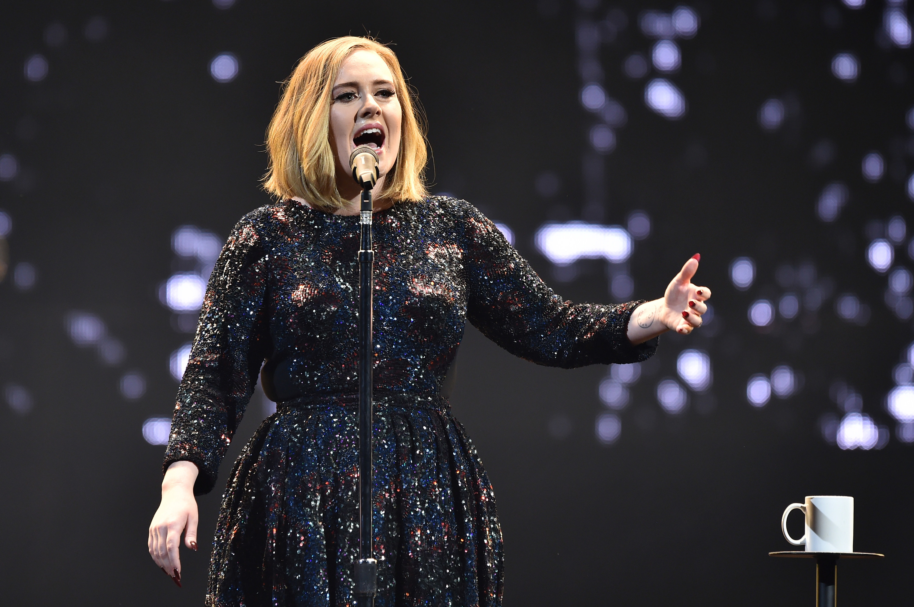 Adele sings with her arm stretched out