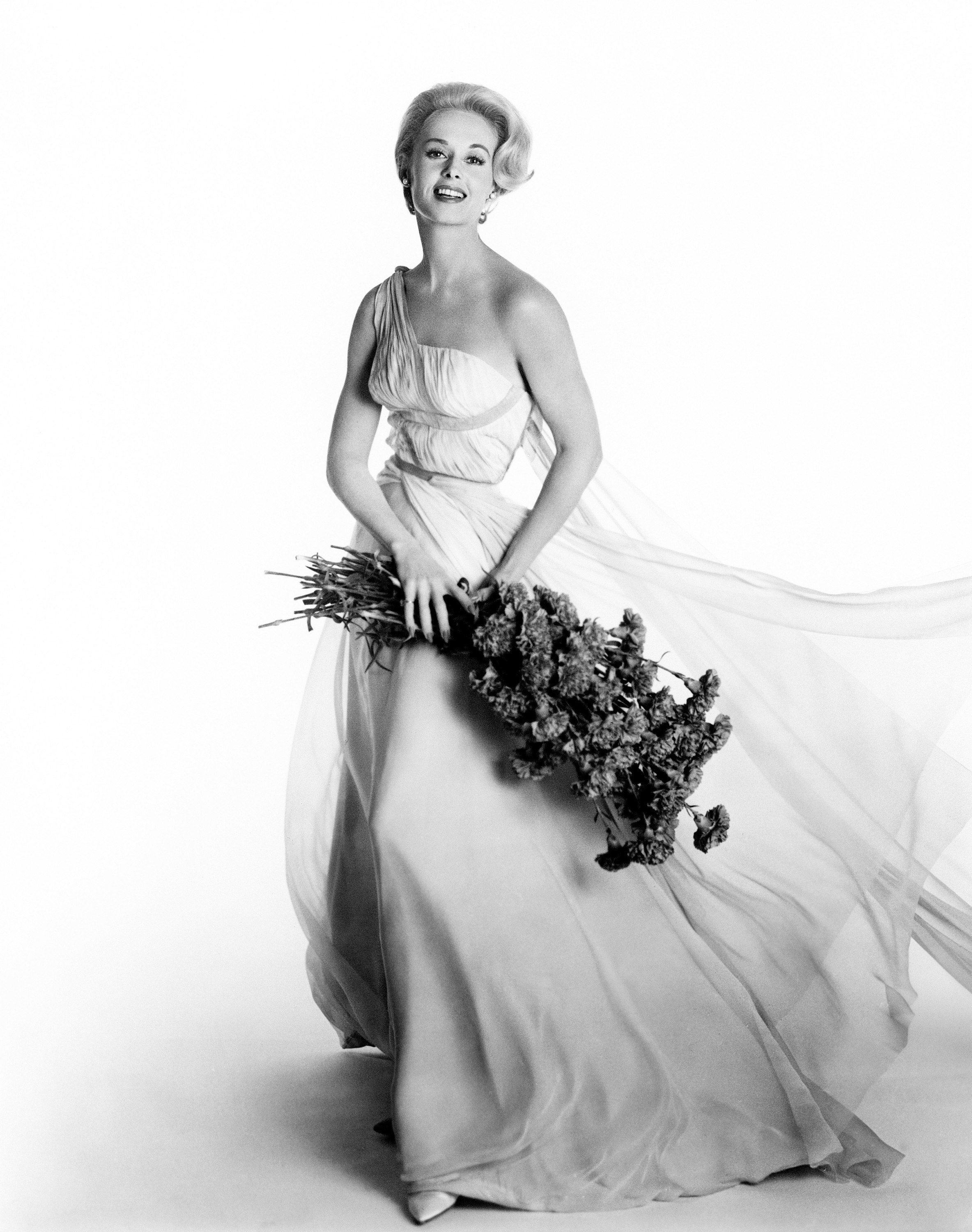 Hedren poses with a flowing dress holding a bouquet of flowers