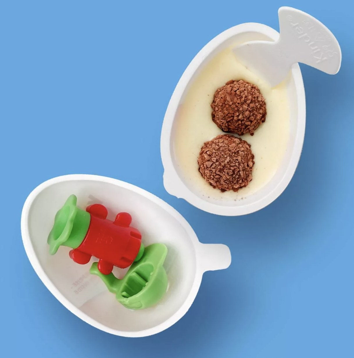 A Kinder Joy egg open to reveal a small toy in one half and creme with chocolate in the other