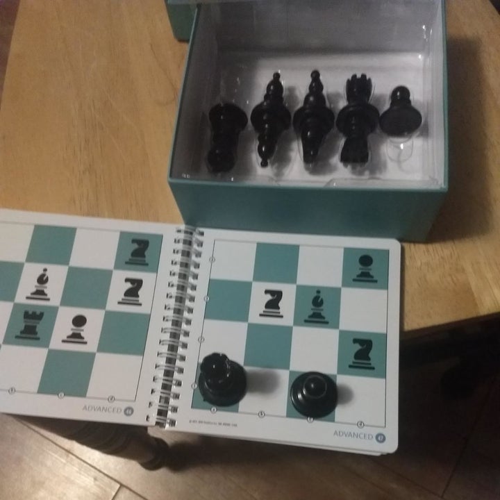 Reviewer image of open box with chess pieces on top of playing book