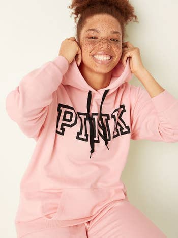 a model in a light pink hoodie with the word 