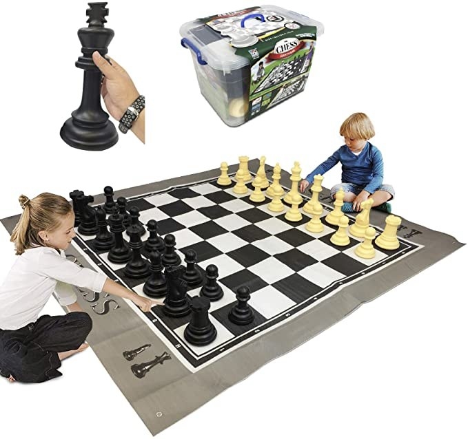 Models playing with giant chess set, model holding large black chess piece, and plastic bin filled with giant chess pieces