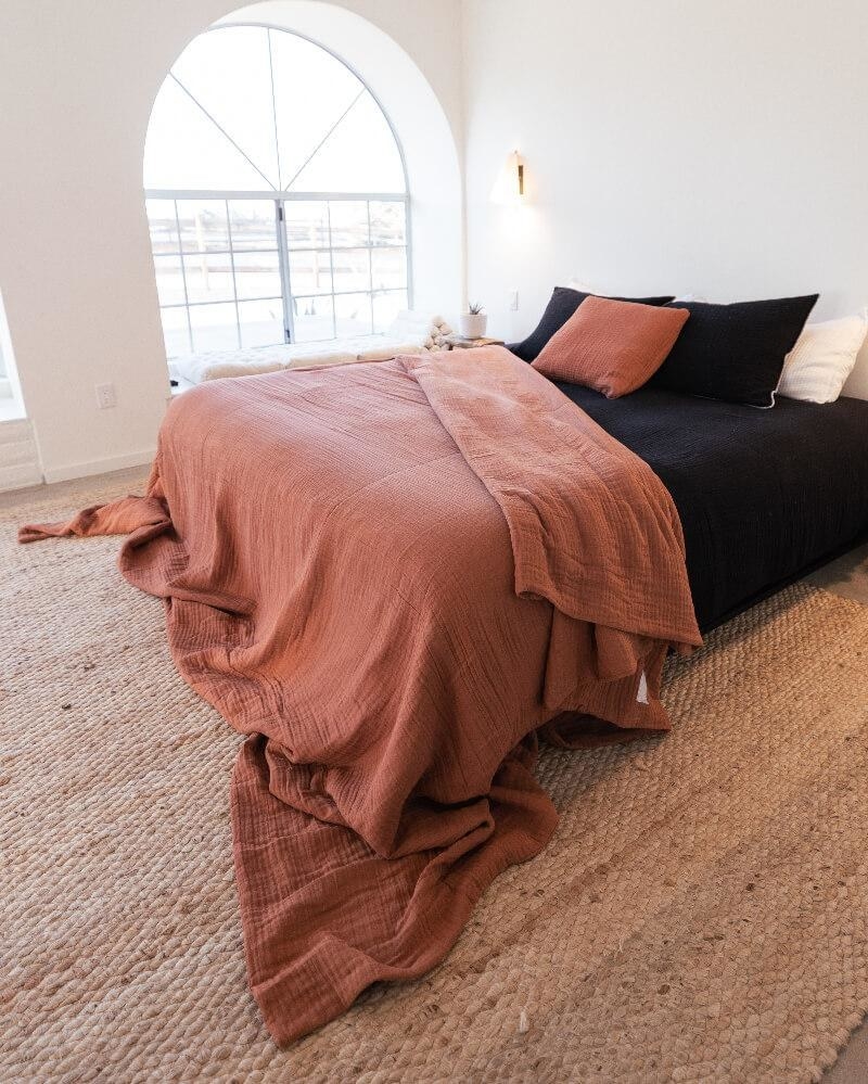the oversized blanket in rust draped over a bed
