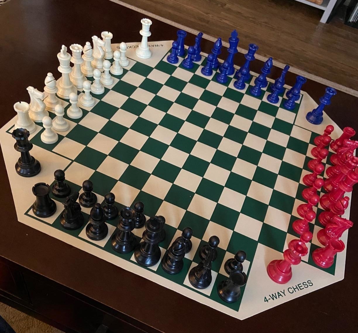 Reviewer image of four-way chessboard set up with red, black, white, and blue chess pieces