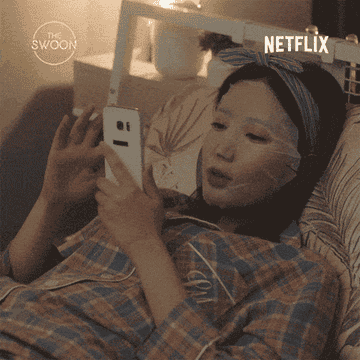 Gif of character in &quot;The Swoon&quot; scrolling on phone and wearing sheet mask