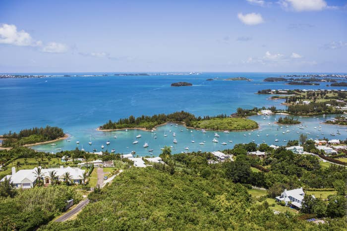 Boats floating in the bay of Bermuda with small lush islands surround them.