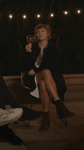 Taylor sitting in a chair and raising a glass of wine