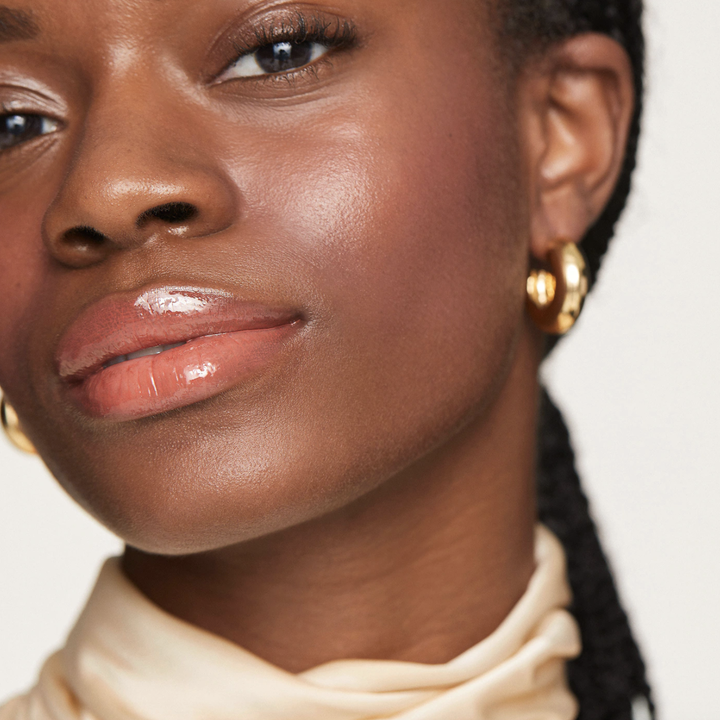 a smiling person looking into the camera; the three products were used on their face