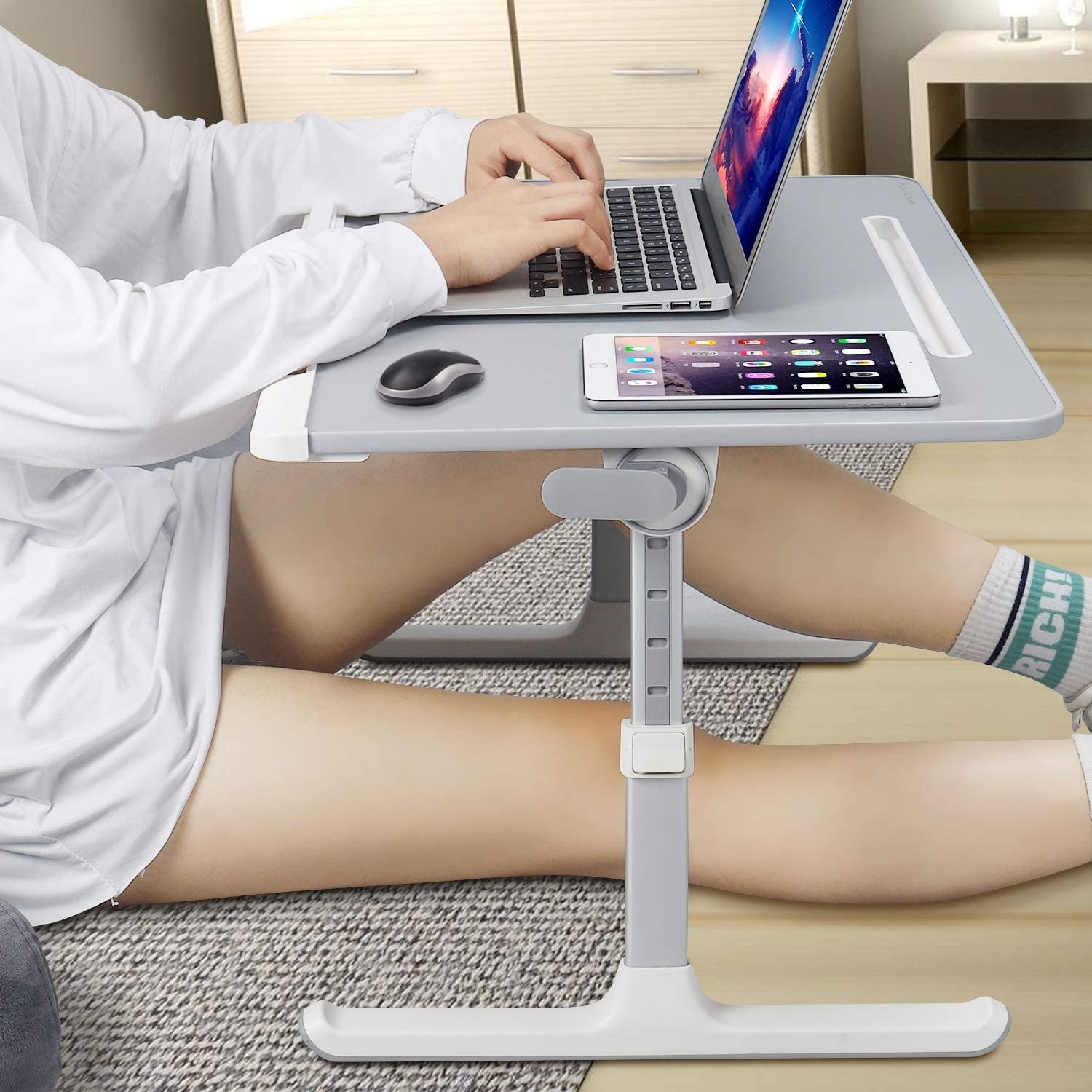 A person working at the desk while sitting on a floor