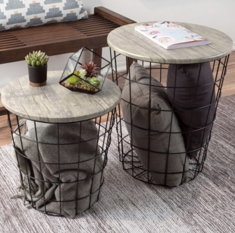 the nesting tables with blankets and pillows in the wire basket portion