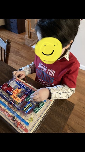reviewer's photo of their child tinkering with the parts on a plastic grid