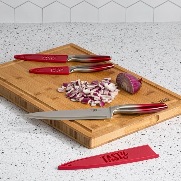 The set of Tasty knives on a cutting board with a diced onion.