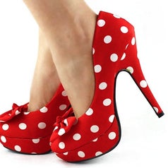 A model wearing a pair of stiletto platform heels in red/white polka dot