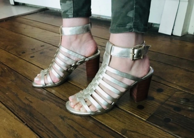 A reviewer wearing a pair of champagne strappy sandals