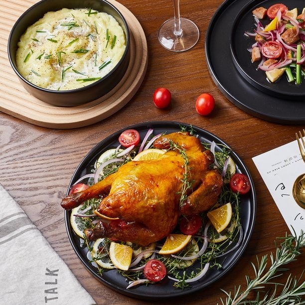 The black, round dinnerware with a roast turkey and mashed potatoes.