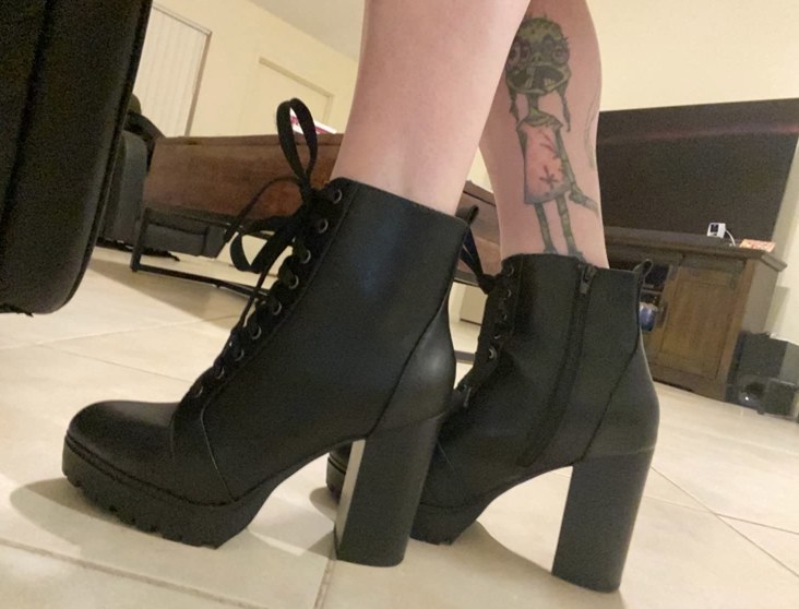 A reviewer wearing black lace up heeled boots