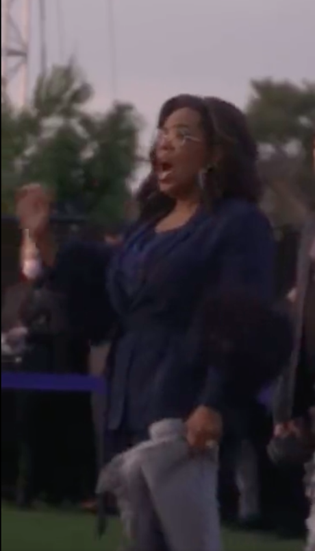 Oprah standing and singing during the concert