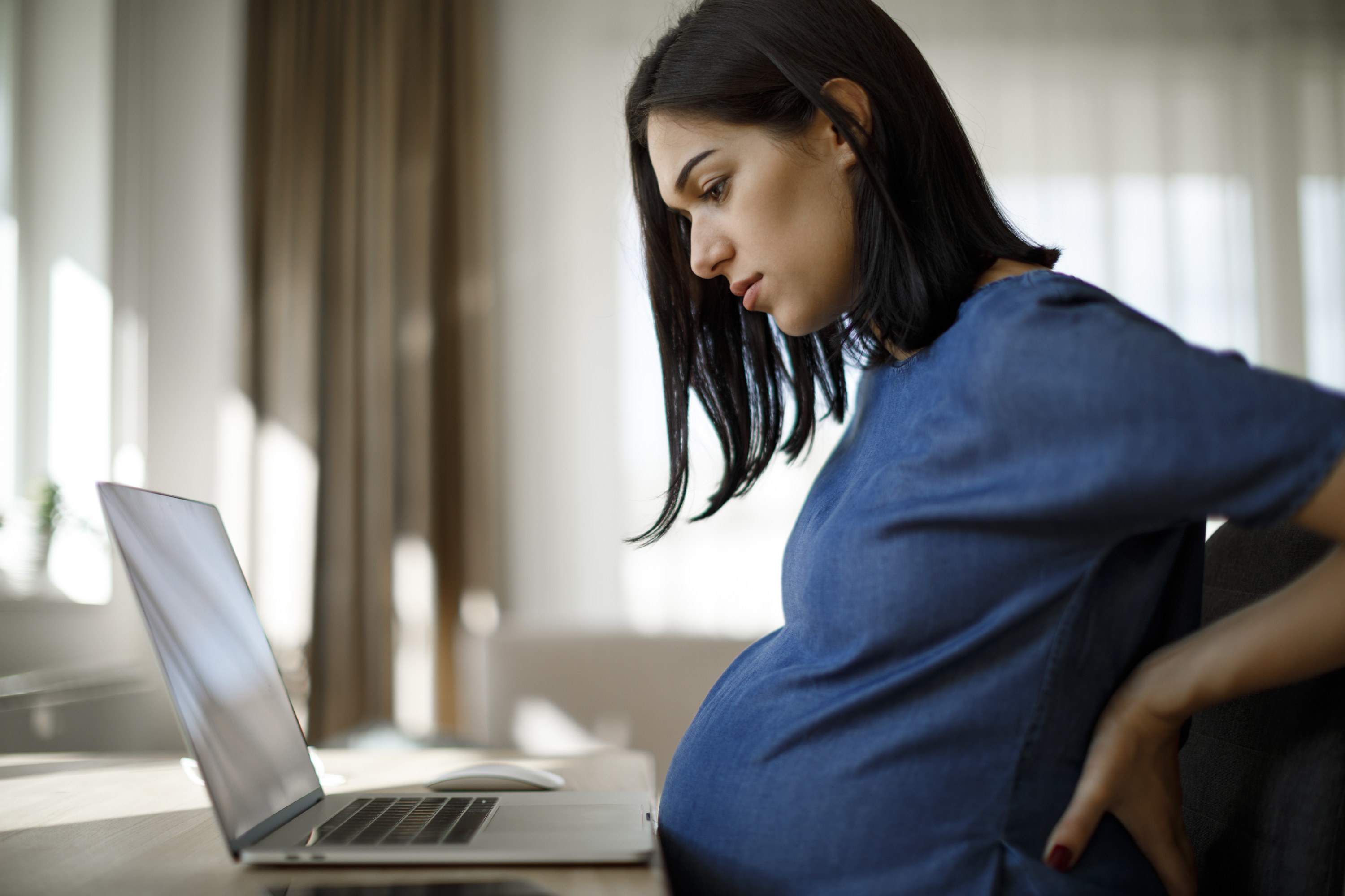 Pregnant woman with a backache working from home