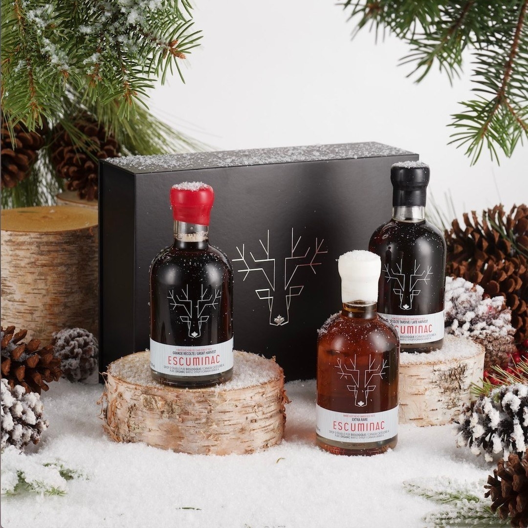 a set of three bottles of artisanal maple syrup nestled into a snowy scene