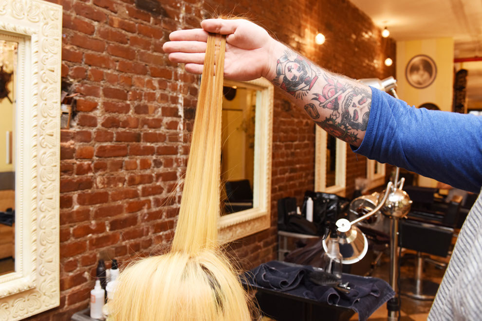 A hand holding up a strand of bleached blonde hair